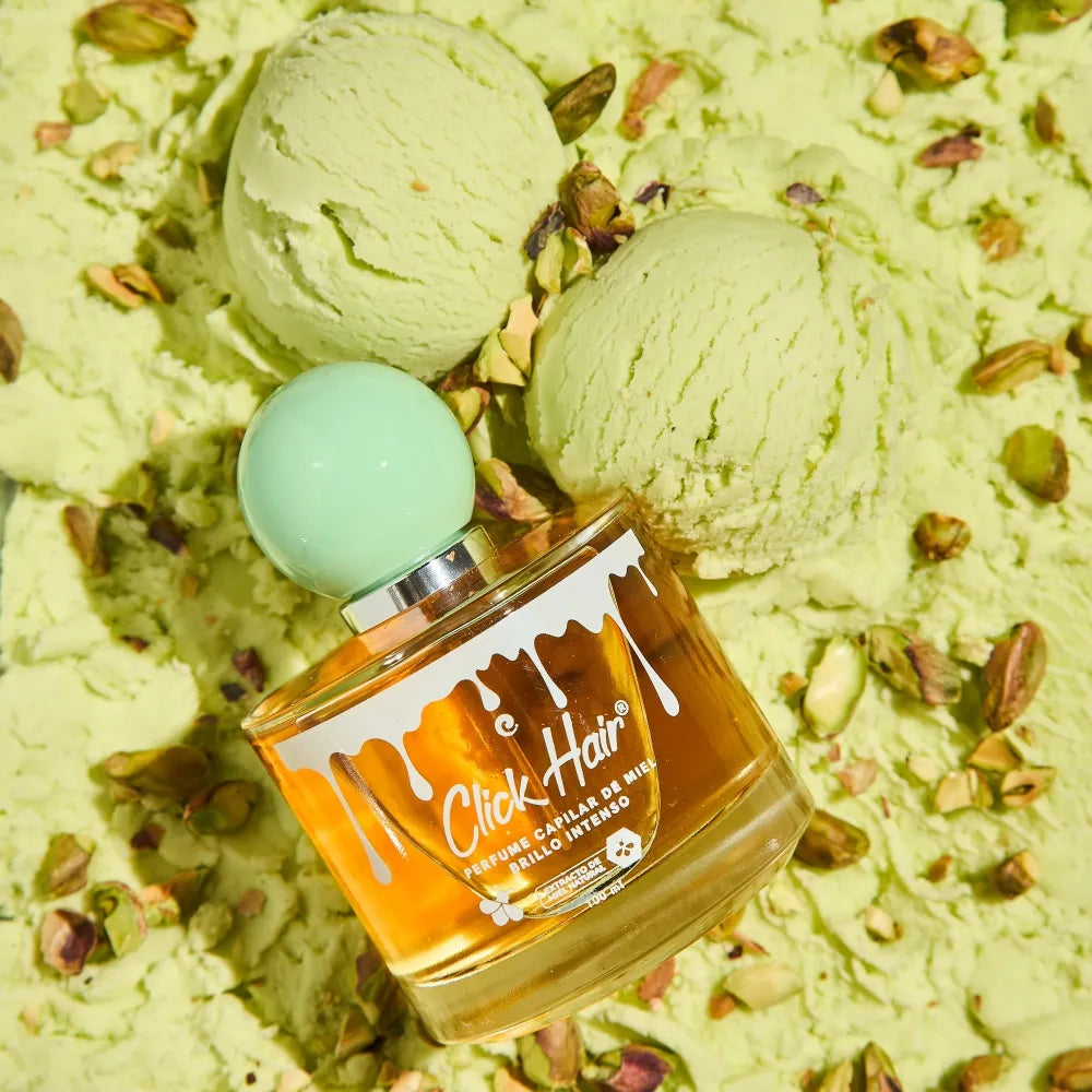 Mujer con cabello ondulado sosteniendo el perfume capilar Click Hair de miel y pistacho 100 ml