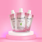 Tres sobres rosados de Crema Depilatoria Facial Lampiña de 15 g sobre un pedestal blanco con fondo rosado