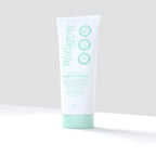 Producto recostado → Shampoo Exfoliante Capilar Milagros 200g recostado sobre superficie blanca, empaque blanco con diseño verde menta