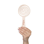 Cepillo Anti Enredo Milagros beige – mano sosteniendo el cepillo con diseño espiral