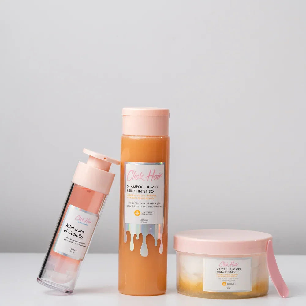 Kit de miel Click Hair sobre fondo gris, con shampoo al centro, miel capilar inclinada y mascarilla con espátula.